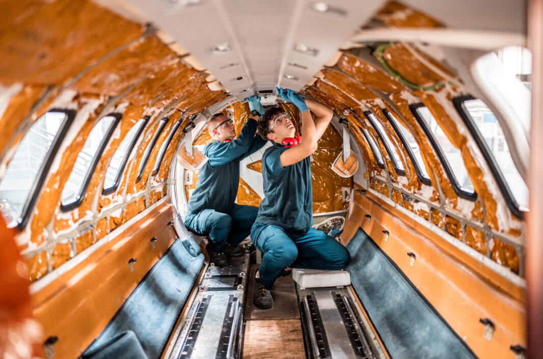 Two maintenance mechanics repairing the interior of the jet airplane