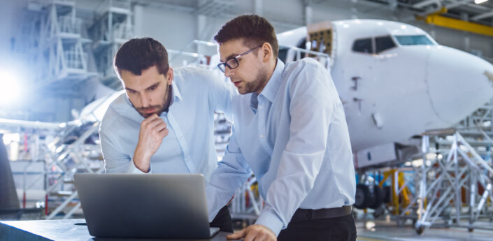Two Aircraft Mechanics Working and Having Conversation next to Laptop Computer